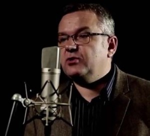 Zdjęcie Artura Andrusa z mikrofonem.